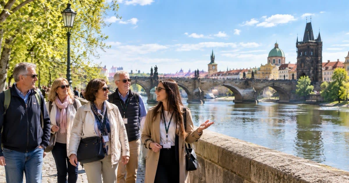 Grupo de viajeros mayores con su guía junto al río Moldava y el Puente de Carlos en Praga